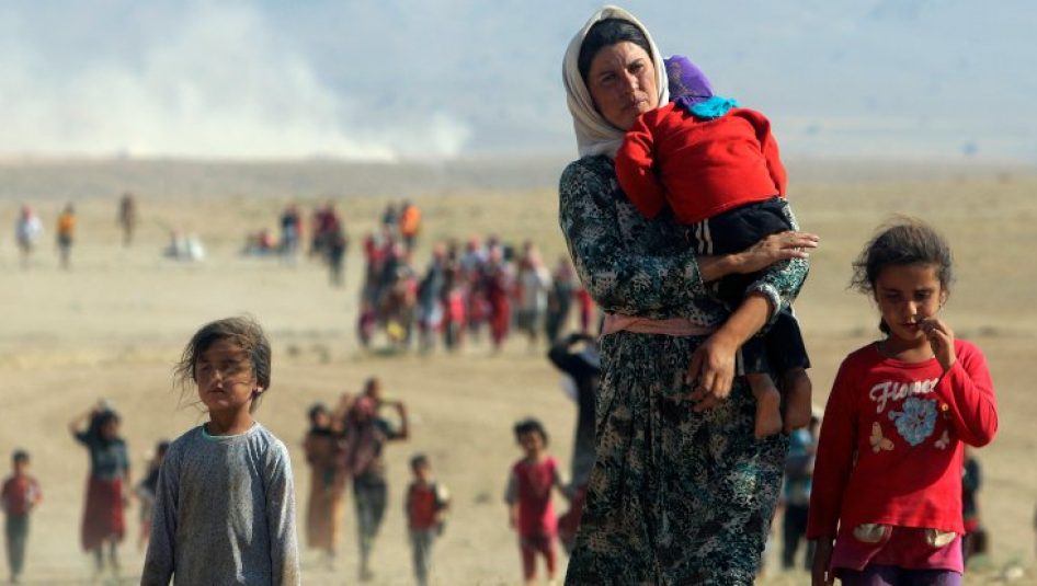 Displaced people from the minority Yazidi sect, fleeing violence from forces loyal to the Islamic State in Sinjar town walk towards the Syrian